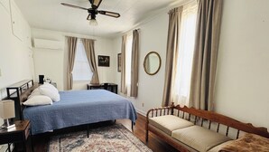 Camera da letto con un letto, comodino, poltrona, divano e ventola a soffitto.