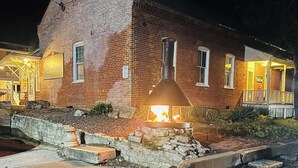 Un edificio in mattoni con un braciere di fronte, un cartello con la scritta 'Nestle Inn' e un portico con posti a sedere all'aperto.