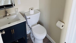 A bathroom with a white sink, dark cabinets, a toilet, and a mirror. - Nestle Inn is a charming, historic hotel located in the heart of Hermann, MO (Hermann)