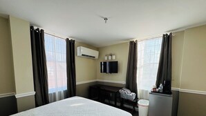 A hotel room with a bed, a desk, a TV, and a refrigerator. - Nestle Inn is a charming, historic hotel located in the heart of Hermann, MO (Hermann)