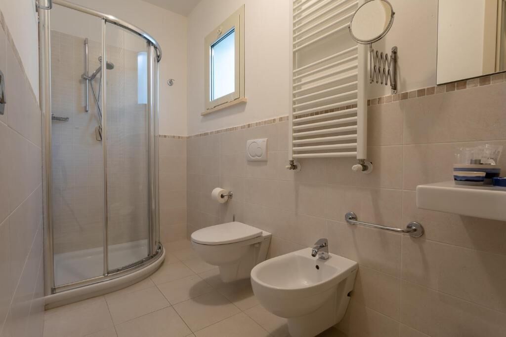 A bathroom with a glass-enclosed shower, a toilet, a bidet, and a sink.