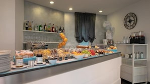 A buffet setup with various food items, a clock, and a fan on the wall. - Hotel gimmi (Rimini)