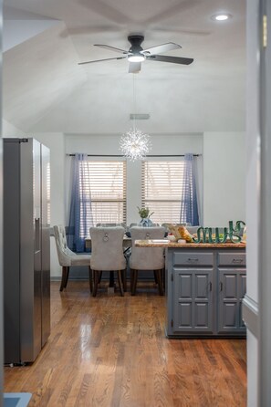 Una cocina moderna con comedor, piso de madera y ventilador de techo.