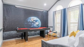 Une pièce équipée d’une table de billard, d’un télescope et ornée d’une fresque représentant la Terre.