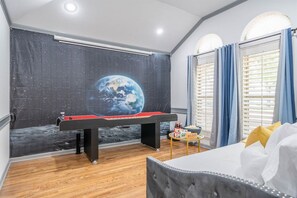 Una habitación con mesa de billar, telescopio y un mural de la Tierra.