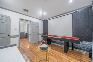 A room with a pool table, a bowl of snacks, and a bed.