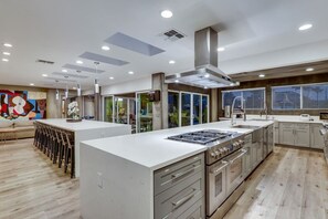 A modern kitchen with a central island, stainless steel appliances, and a large window. - Luxury Vegas Compound: Waterfall Pool & Full Court (Las Vegas)