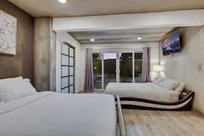 A hotel room with two beds, a sliding glass door to a balcony, a flat-screen TV, and a painting on the wall. - Luxury Vegas Compound: Waterfall Pool & Full Court (Las Vegas)