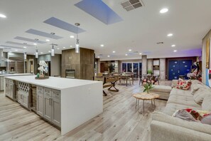 A spacious kitchen with a central island, a dining area with a wooden table, and a living room with a sofa and a coffee table. - Luxury Vegas Compound: Waterfall Pool & Full Court (Las Vegas)