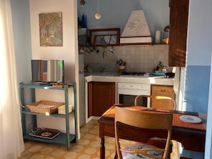 A kitchen with a TV, shelves, a dining table, and chairs. - Pisa Centro a 10-minute walk, private parking, Wi-FI (Pisa)