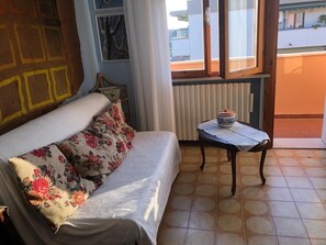 A room with a sofa, a table with a container, a radiator, and a window with a view. - Pisa Centro a 10-minute walk, private parking, Wi-FI (Pisa)