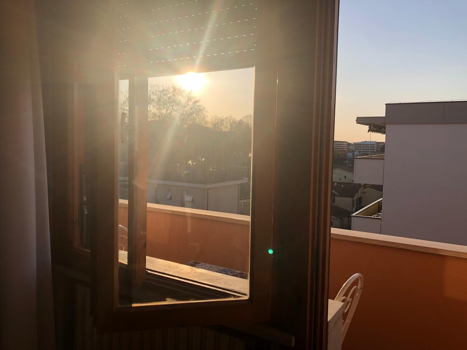 A window with a view of a building and a chair inside.