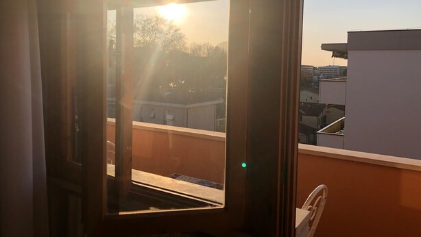 Ein Fenster mit Blick auf ein Gebäude und ein Stuhl im Raum.