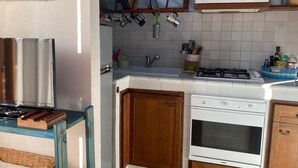 Eine Küche mit weißen Schränken, einem Gasherd, einem Backofen und einer Mikrowelle.