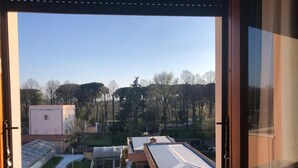Blick aus einem Fenster auf ein Wohngebiet mit Häusern, Bäumen und einem klaren Himmel.