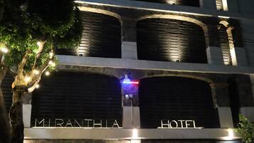A hotel with a sign reading 'MIRANTHIA HOTEL,' multiple balconies, and a gated entrance.