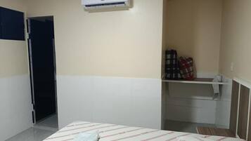 Habitación de hotel con cama, armario, escritorio pequeño y aire acondicionado.