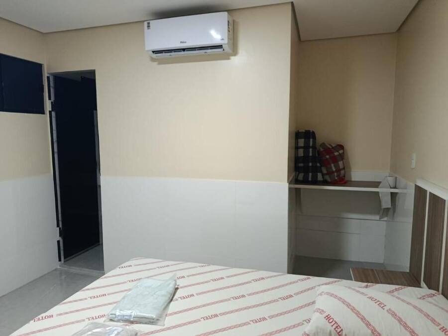 Habitación de hotel con cama, armario, escritorio pequeño y aire acondicionado.