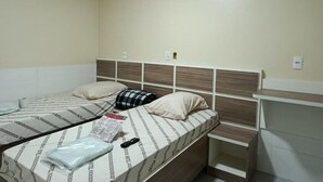 Un dormitorio con dos camas, cabeceros, mesitas de noche y un interruptor de luz en la pared.