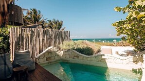 Una piscina con un muro de piedra, un muelle de madera y vistas al océano.