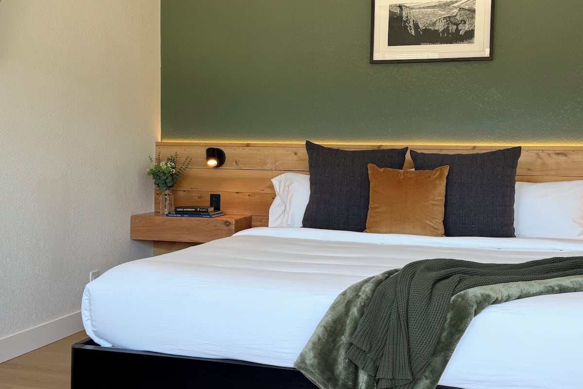 A modern bedroom with a bed, nightstand, and a framed picture on the wall.