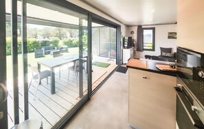 A modern kitchen with a large window, a dining area with outdoor seating, and a small living space. - Cozy home in Olonzac with heated swimming pool (Olonzac)