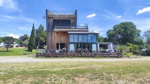 Un bâtiment moderne à deux étages, doté d’une grande façade en verre, d’un revêtement extérieur en bois et d’un espace extérieur aménagé avec des sièges.