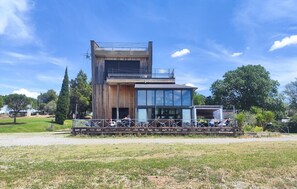 A modern two-story building with a large glass facade, a wooden exterior, and a covered outdoor seating area. - Cozy home in Olonzac with heated swimming pool (Olonzac)