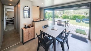 Une cuisine moderne avec un coin repas, de grandes fenêtres et une vue sur le jardin.