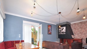Una sala de estar con una mesa de madera, sofá rojo y chimenea de ladrillo.