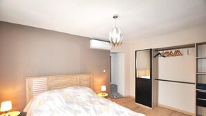 Un dormitorio con cama, lámparas de noche, armario y aire acondicionado.