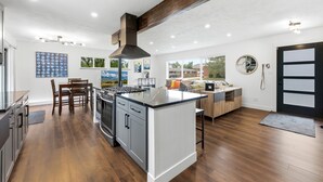 Cocina moderna con isla central, piso de madera y un amplio ventanal.