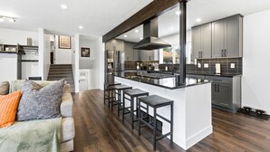 Una cocina moderna con una isla central, armarios grises y una escalera que lleva a otro nivel.