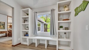 Ein Zimmer mit einer eingebauten Sitzbank, weißen Regalen und einem Fenster mit Vorhängen.
