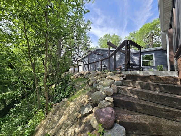 A stone staircase leading to a house with a covered porch, surrounded by trees.