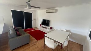 A modern living room with a sofa, a dining table, and a TV.