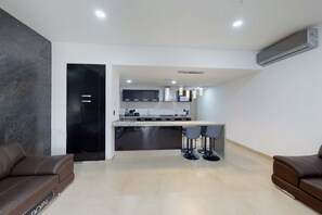 A modern kitchen with a central island, bar stools, and a built-in dishwasher. - Cancun Malecon 2BR/2BA | Pool, Gym & Terrace (Cancún)