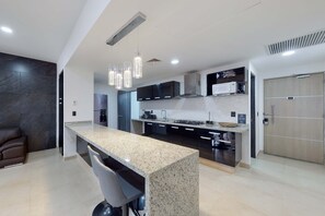 A modern kitchen with a granite countertop, stainless steel appliances, and pendant lighting. - Cancun Malecon 2BR/2BA | Pool, Gym & Terrace (Cancún)