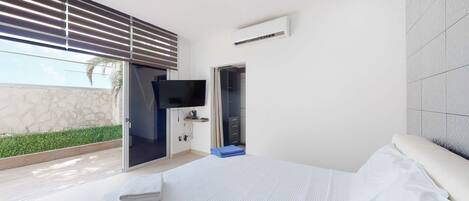 A modern bedroom with a large bed, a TV, and a sliding door leading to a balcony.