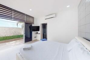 A modern bedroom with a large bed, a TV, and a sliding door leading to a balcony. - Cancun Malecon 2BR/2BA | Pool, Gym & Terrace (Cancún)