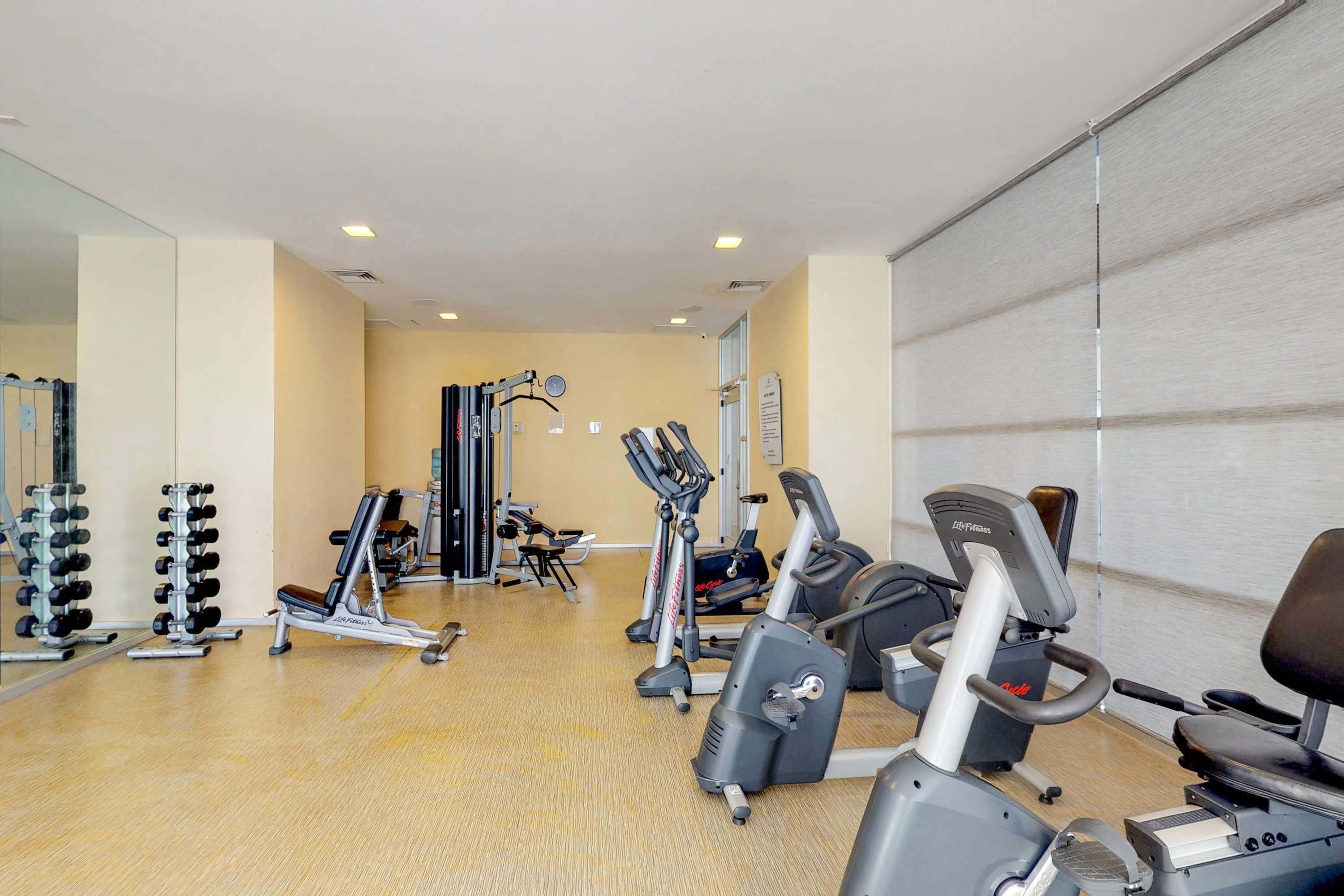 Une salle de sport équipée de matériel d’exercice, dotée d’un miroir et d’un plancher en bois.