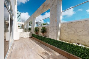 A modern building with stone walls, large windows, and a green hedge. - Cancun Malecon 2BR/2BA | Pool, Gym & Terrace (Cancún)