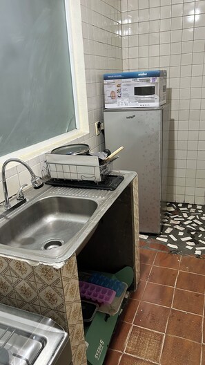 A kitchen with a sink, a microwave, and a small refrigerator.