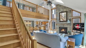 Ein geräumiger Wohnbereich mit Treppe, Kamin, Fernseher und Essbereich.