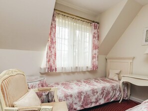 A bedroom with a single bed, a chair, a small table, and a window with curtains. - 4 Star Holiday Home in Faaborg (Faaborg)