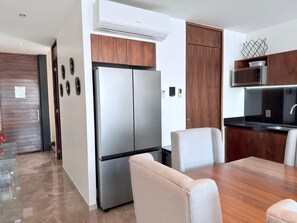 Eine moderne Küche mit einem Edelstahl-Kühlschrank, Holzschränken, einer Mikrowelle und einem Essbereich mit Stühlen.