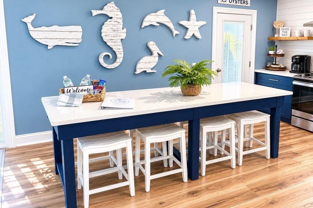 A kitchen with a blue and white color scheme, a white island with stools, and wall decorations of sea creatures.