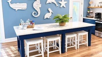 A kitchen with a blue and white color scheme, a white island with stools, and wall decorations of sea creatures.