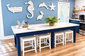 A kitchen with a blue and white color scheme, a white island with stools, and wall decorations of sea creatures. - Perfect Family Home | Private Pool • Walk to Beach (Panama City Beach)