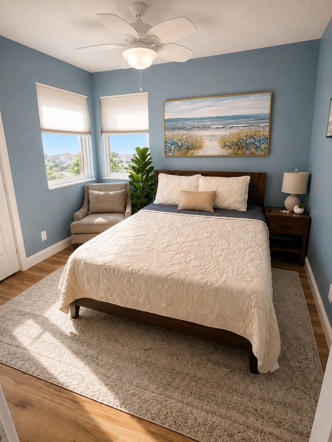 A bedroom with a bed, a nightstand, a lamp, a plant, and a painting on the wall.